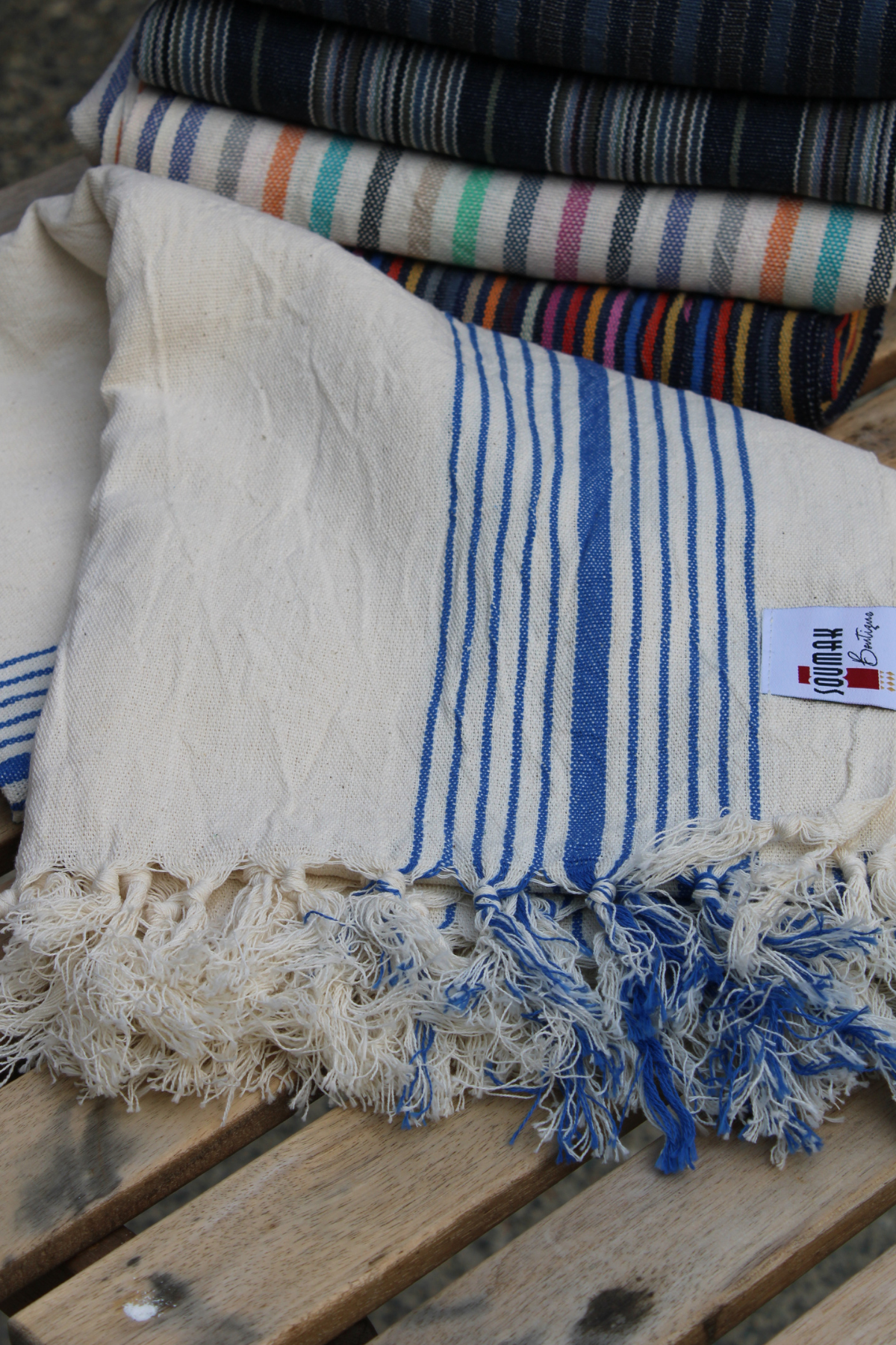 A beautifully folded Organic Turkish Cotton Towel in white with blue stripes, showcasing high-quality craftsmanship. Available at Soumak Boutique, Vancouver, BC, Canada, inside the Kids Market on Granville Island.