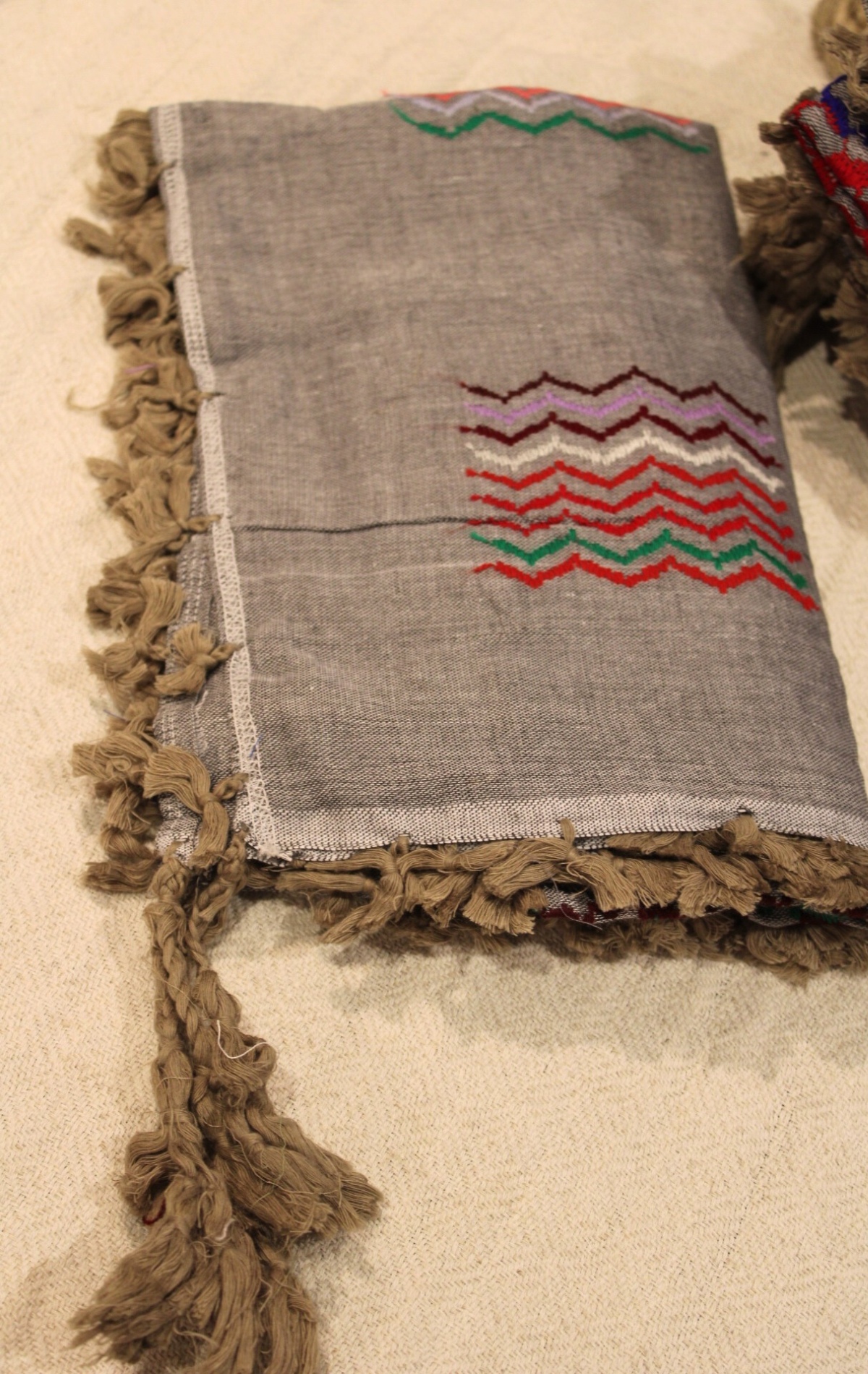 Showcasing the Grey Kuffiyeh scarf with brown tassels, emphasizing its sophisticated design and artistic flair.