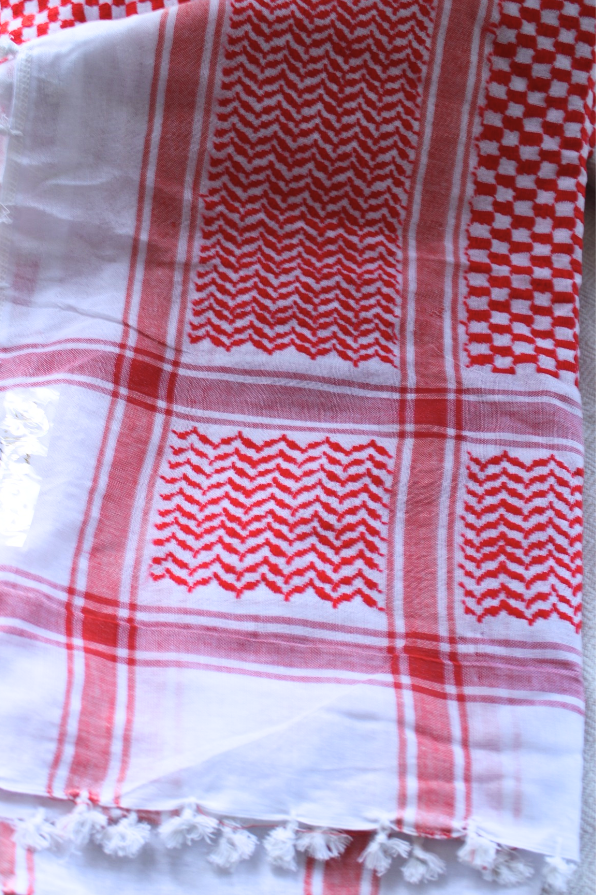 Handwoven red and white Keffiyeh scarf with delicate fringe tassels. A beautiful blend of craftsmanship and tradition, perfect for making a bold cultural statement.