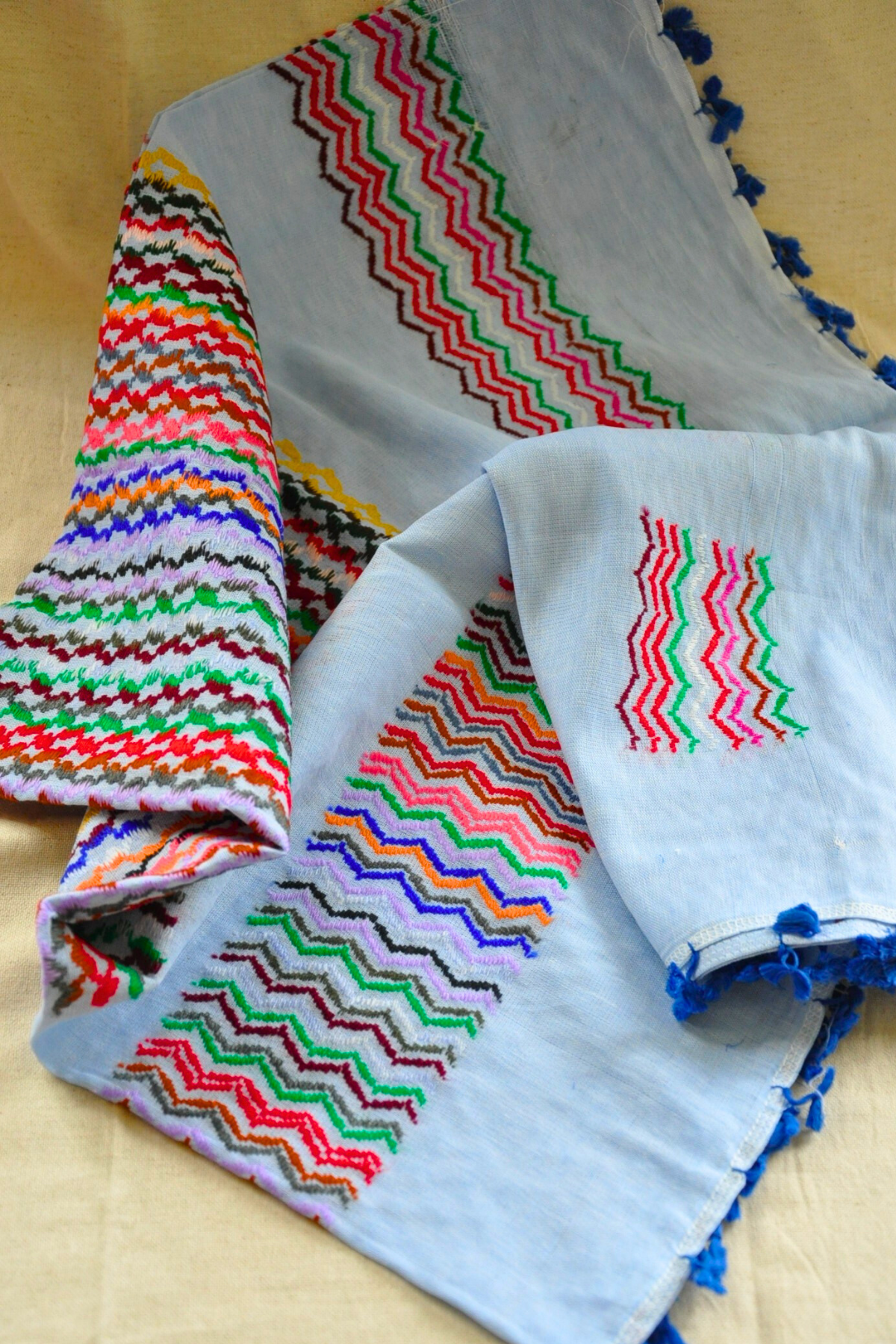 Light Blue Kuffiyeh scarf elegantly styled on a table, illustrating its versatility and vibrant appeal for any occasion.