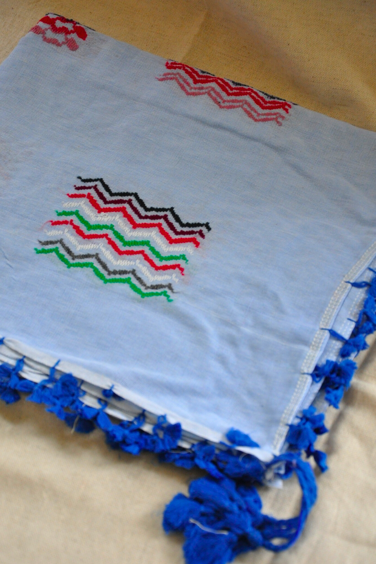 Light Blue Kuffieyeh scarf adorned with dark tassels, emphasizing its captivating design and handcrafted quality.