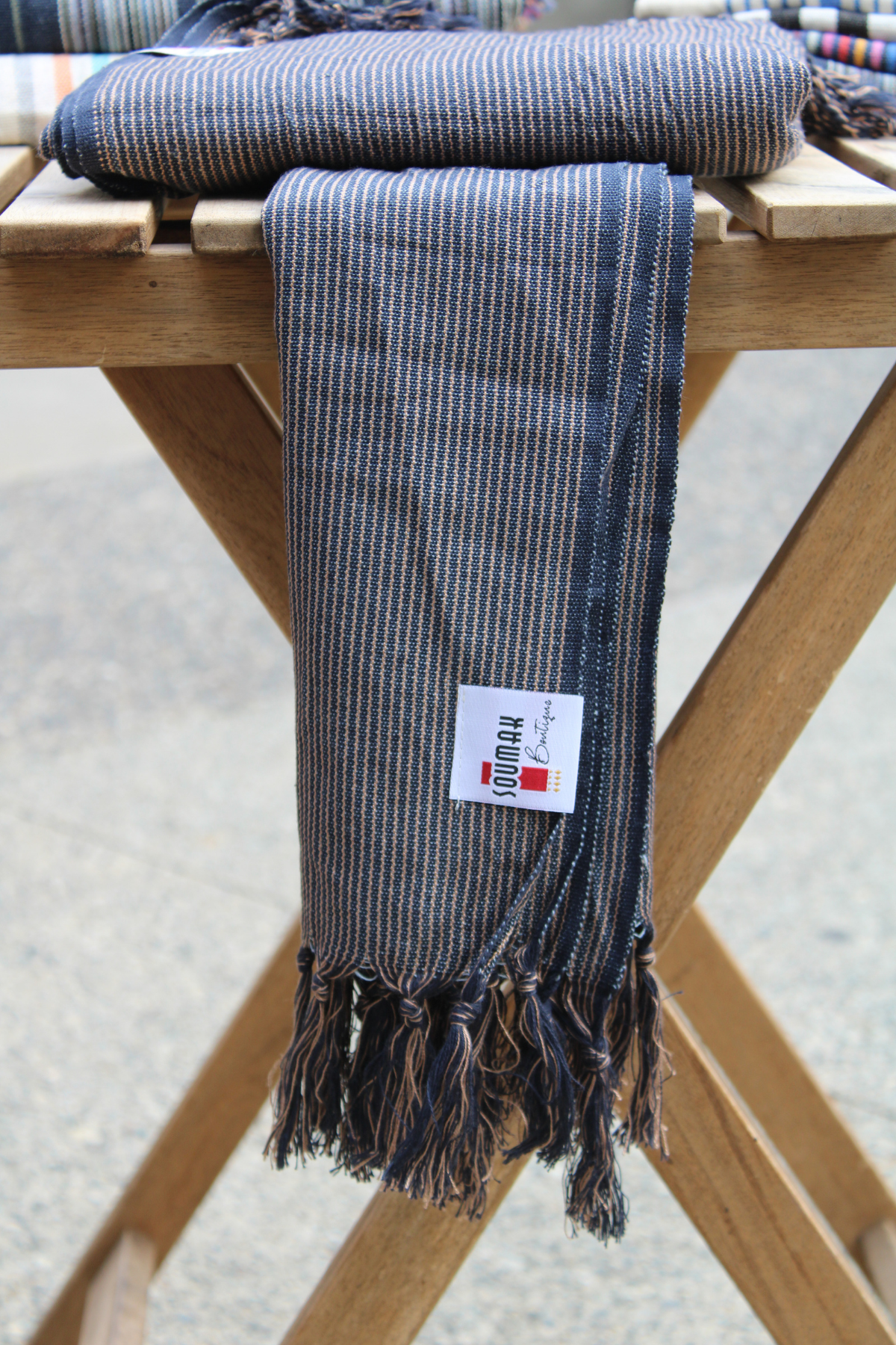 Presenting our Organic Turkish Cotton Hand Towel displayed beautifully on a wooden table, emphasizing the rich dark blue herringbone design. Visit us at Soumak Boutique, Granville Island, Vancouver, BC, Canada.
