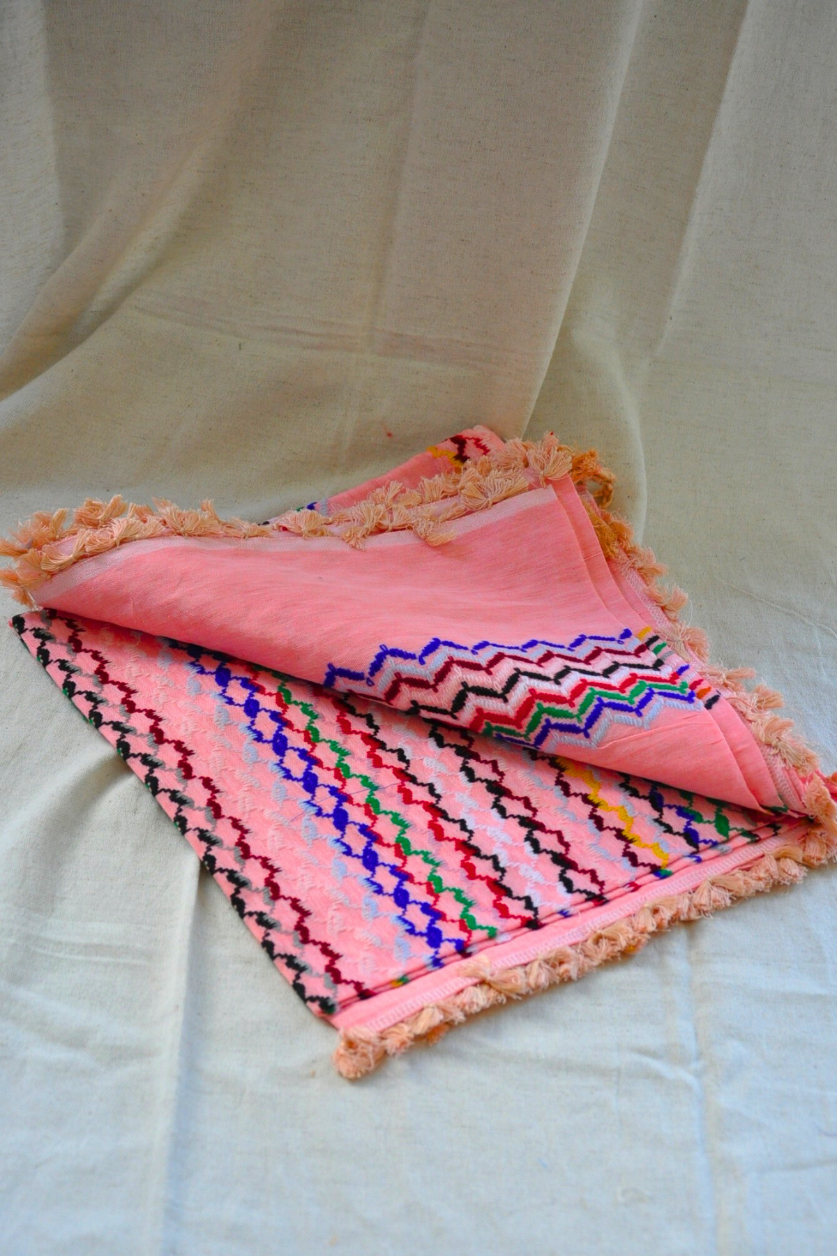 Focusing on the Peach Kuffiyeh scarf adorned with matching tassels, showcasing its sophisticated design and artistic flair.