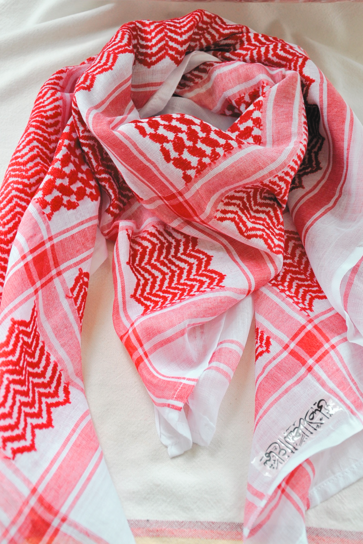 Traditional red and white Keffiyeh scarf designed without tassels for a simple yet powerful look. Handmade to embody the essence of Middle Eastern culture and craftsmanship.