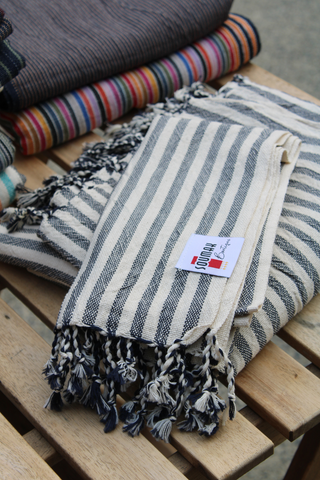 A vertical display of our Turkish hand towel in black and white stripes, located at Soumak Boutique, Kids Market, Vancouver, BC, Canada.