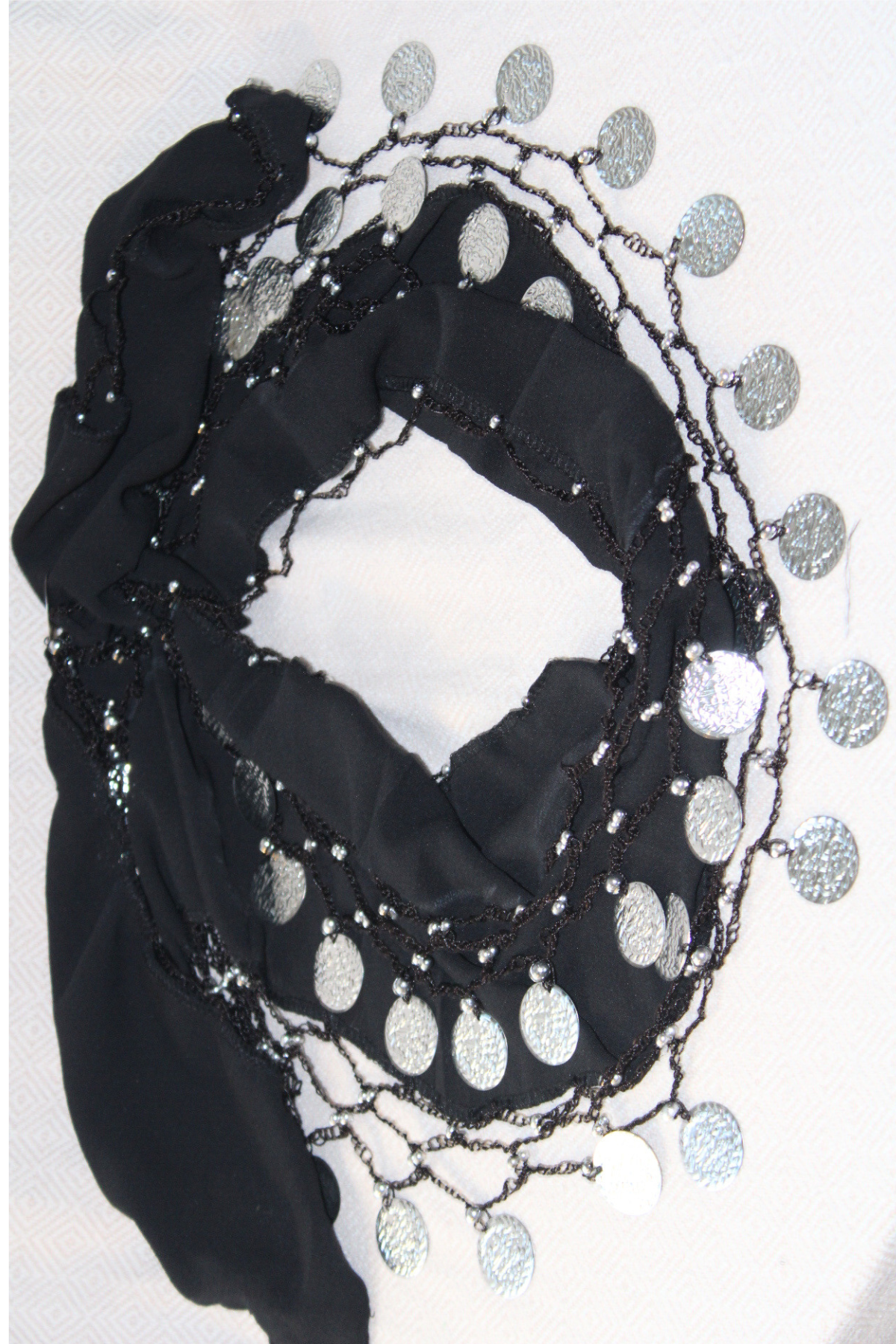 A sleek black belly dance waist chain with two layers of silver coins. The dark color contrasts beautifully with the shimmering silver, offering a striking and elegant accessory for your dance routine.